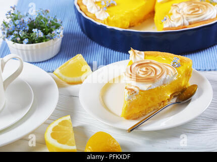 Morceau de tarte au citron classique français ou tarte au citron sur une assiette et dans un plat allant au four avec une crème anglaise remplissage citron meringue décoré de roses et d'e Banque D'Images