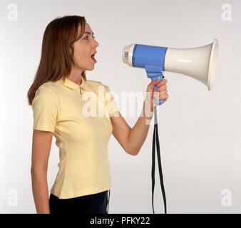 Jeune femme crier par mégaphone, side view Banque D'Images
