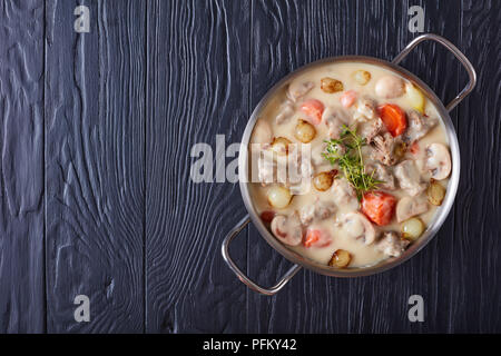 Ragoût de veau crémeux ou blanquette de veau - Morceaux de viande de veau à l'étuvée avec vitrage champignons oignons perles, et légumes en cocotte, le français authentique Banque D'Images