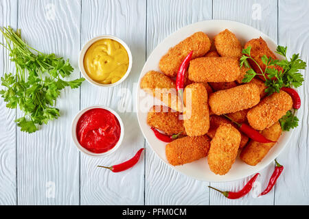 Espagnol délicieux en friture, croquetas croquettes de pomme de terre sur une plaque blanche avec des piments, de la moutarde et de la sauce tomate sur une table en bois, vue d'un Banque D'Images