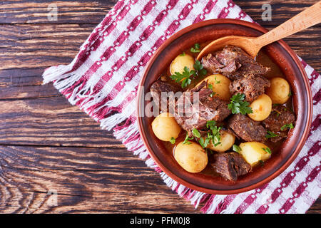 Ragoût de boeuf chaud avec de tendres cubes de viande, pommes de terre nouvelles, ensemble l'oignon et les herbes dans un bol d'argile sur la vieille table en bois rustique avec une cuisine irlandaise, serviette, hor Banque D'Images