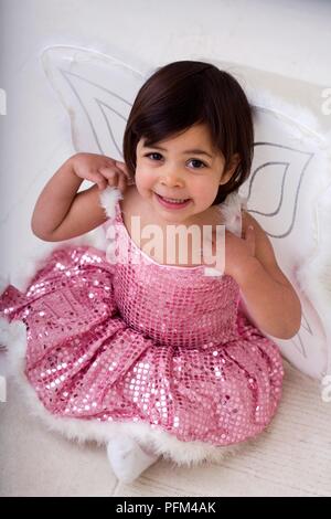 Girl wearing tutu rose cuir et les ailes de papillon, looking up, smiling Banque D'Images