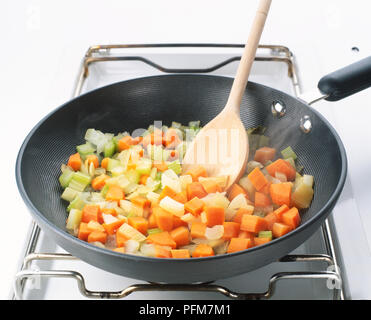 Close-up de brunoise de légumes et d'une cuillère de bois dans une poêle. Banque D'Images