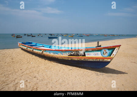 Peintes de couleurs vives, mais essuyé, bateau de pêche sur la plage de la côte de Malabar sur la mer d'Oman. De nombreux bateaux sont amarrés dans la mer derrière. Banque D'Images