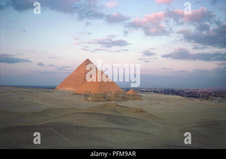 L'Égypte, les formations nuageuses sur les pyramides de Gizeh au coucher du soleil, les pyramides en rouge par un soleil couchant, propagation de la ville en arrière-plan. Banque D'Images