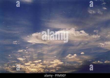 Altocumulus castellanus lumière par le soleil rouge, baigné de lumière du soleil couchant, ciel bleu derrière. Banque D'Images