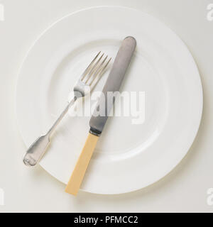 Le couteau et la fourchette sur une assiette blanche, vue d'en haut Banque D'Images