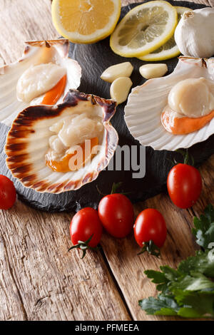 Spécialités de la mer pétoncles crus dans un coquillage et légumes frais sur une table verticale. Banque D'Images