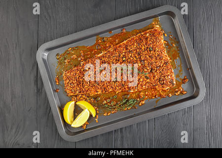 Délicieux filet de poisson blanc cuit avec des graines de citrouille et de tournesol broyées croûte épicée sur une tôle à biscuits au thym et les rondelles de citron, vue d'en haut, Banque D'Images