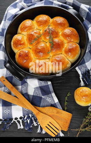 Douce et moelleuse du dîner fait maison petits pains dans le plat de cuisson avec des essuie-tout et spatules en bois sur une table de cuisine, vue verticale d'en haut Banque D'Images