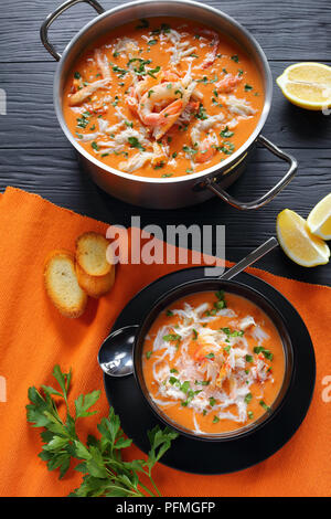 Délicieux chaud ou en biscuit riche soupe de viande de crabe de l'alaska déchiquetés, crevettes et légumes dans une casserole en acier inoxydable et en noir bol avec cuillère Banque D'Images