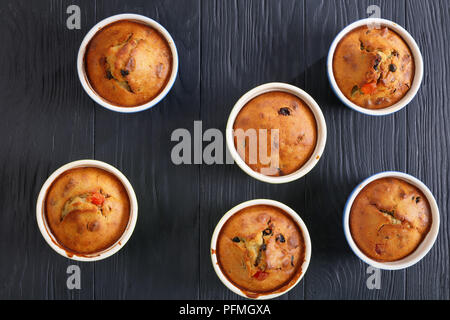 Délicieux faits maison fraîchement préparés Bananes et noix et raisins Muffins dans des ramequins en céramique sur table en bois noir, vue de dessus, close-up Banque D'Images