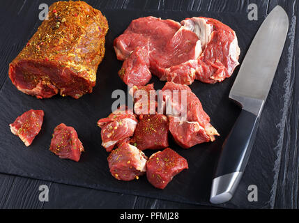 Close-up de matières premières fraîches filet de boeuf haché assaisonné d'épices sur une plaque en ardoise noire avec couteau, vue de dessus Banque D'Images