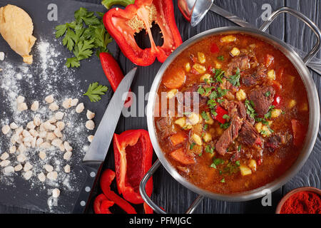 De bœuf chaud délicieux goulasch hongrois avec le paprika, petit oeuf pâtes, légumes et épices dans un pot. les ingrédients et verser sur la table de cuisine classique, re Banque D'Images