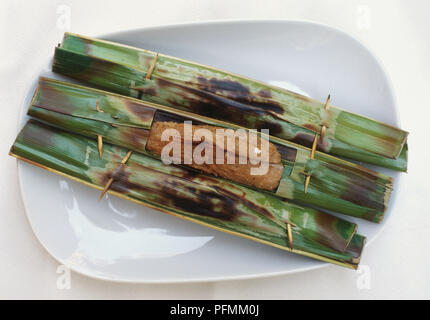 La cuisine malaisienne, Otak otak-pâte de poisson, enveloppés dans des feuilles de coco, section de feuille supprimée révélant de coller, de petits bâtonnets de bois fixant les feuilles. Banque D'Images