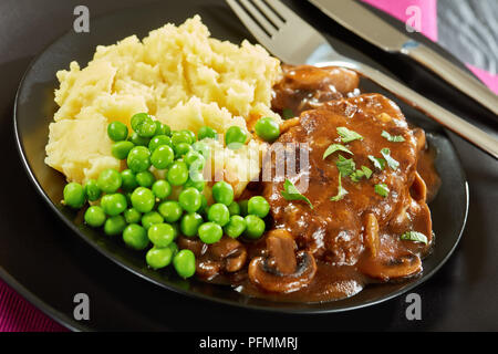 Close-up de partie de sex salé les steaks juteux salisbury avec sauce oignon champignons servi avec une purée de pommes de terre et les pois verts sur les plaques noires wit Banque D'Images