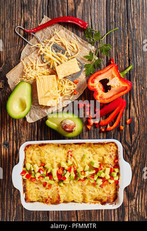 Délicieux enchiladas chaud maison de tortilla de maïs avec de la viande haché, sauce, fromage râpé et des morceaux de piment dans le plat de cuisson arrosé avec de l'avocat Banque D'Images