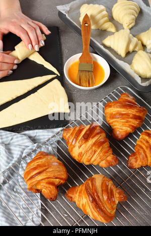 La femme est l'élaboration de la pâte feuilletée en rouleaux crescent pour cuire croissants français. des golden brown de délicieux croissants chauds sont sur circuit de refroidissement g Banque D'Images