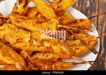 Close-up de grilled satay de poulet sur les brochettes sur une plaque blanche sur table en bois, recette classique, street food, vue d'en haut Banque D'Images