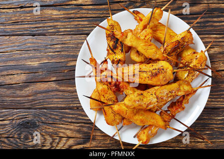 Satay de poulet sur les brochettes sur une plaque blanche sur table en bois rustique, de l'alimentation de rue, recette authentique, vue de dessus, télévision lay Banque D'Images