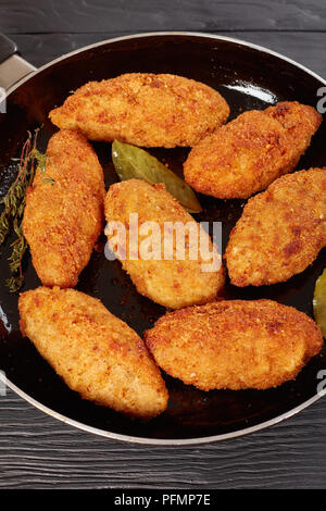 Croquettes de viande pané frit au fromage fondu garniture sur une poêle sur une table en bois, vue verticale de ci-dessus, close-up Banque D'Images