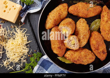 Croquettes de viande juteuse pané frit au fromage fondu garniture sur une poêle sur une table en bois avec des ingrédients à l'arrière-plan, vue horizontale de ab Banque D'Images