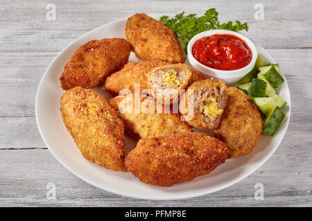 Croquettes de viande panée juteux frits au fromage fondu garniture sur une assiette blanche avec salade de concombre et la sauce tomate, la vue de dessus, close-up Banque D'Images