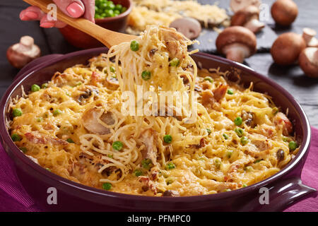 Woman's hand holding est une fourche avec partie des classiques américains, Tetrazzini à la pâte de casserole de viande de volaille, les champignons et le fromage, vue de dessus, cl Banque D'Images