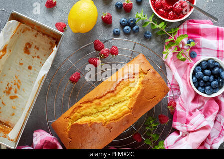 Du gâteau au citron ou pound cake aux fruits rouges remplissant également connu sous le nom de gateau de voyage gâteau sur un tableau concret aux fruits rouges et citron, cui français Banque D'Images