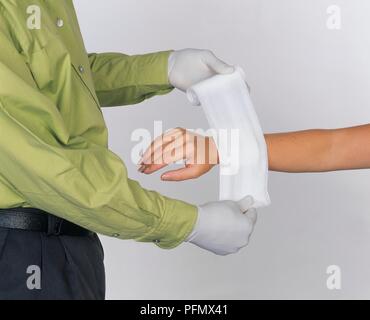 Homme portant des gants chirurgicaux rétractable pansement sur un avant-bras de la femme, close-up Banque D'Images