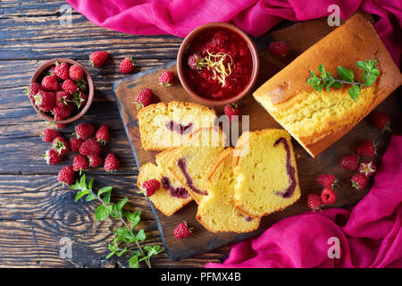 Des tranches de citron pound cake à la confiture de framboises remplissant également connu sous le nom de gateau de voyage gâteau sur une vieille table en bois foncé, style rustique, en français Banque D'Images