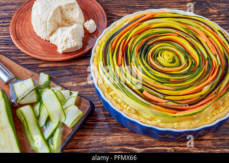 Close-up de spirale de légumes quiche à la courgette, l'aubergine, la carotte avec des tranches de fromage ricotta dans un plat allant au four, sur une vieille table rustique avec dans Banque D'Images