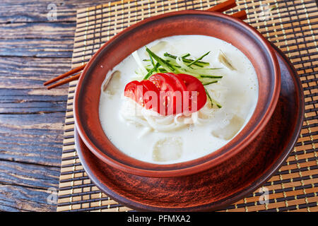 Kongguksu, - délicieux d'été froide soupe coréenne avec du lait de soja et nouilles de riz garnie de lanières de concombre et de tranches de tomate servi dans un bol avec de l'argile Banque D'Images
