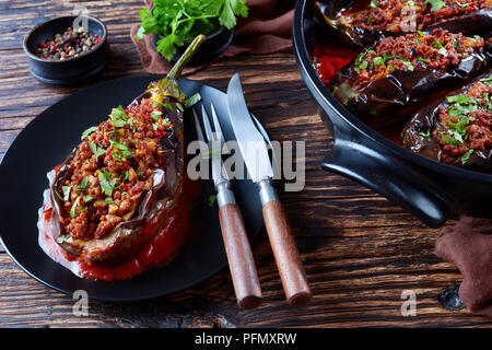 - Karniyarik, Aubergines Aubergines farcies avec du boeuf haché et de légumes cuits au four avec sauce tomate servi sur une plaque avec fourchette et couteau, Turkish cuis Banque D'Images