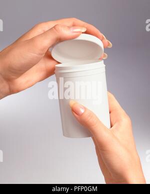 Mains en plastique ouverture bouteille de pilules, close-up Banque D'Images