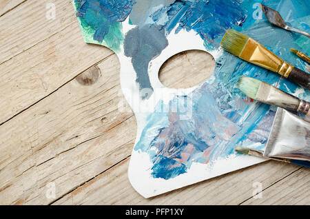 Artiste peinture pinceaux et tubes de peinture à l'huile sur la palette en bois. Les peintures à l'huile mélangée de texture en différentes couleurs. Les instruments et les outils pour les loisirs créatifs. Banque D'Images