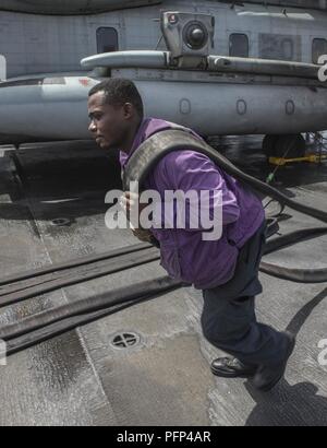 5ème ZONE DES OPÉRATIONS DE LA FLOTTE (23 mai 2018) l'Aviation maître de Manœuvre (carburant) Airman Mark Lee, de Pittsburgh, se déplace d'un tuyau de carburant dans la cabine de pilotage à bord de la classe Wasp-navire d'assaut amphibie USS Iwo Jima (DG 7), le 23 mai 2018. Iwo Jima, homeported à Mayport, en Floride, est le déploiement de la 5e flotte américaine zone d'opérations à l'appui d'opérations de sécurité maritime de rassurer les alliés et partenaires, et de préserver la liberté de navigation et la libre circulation du commerce dans la région. Banque D'Images