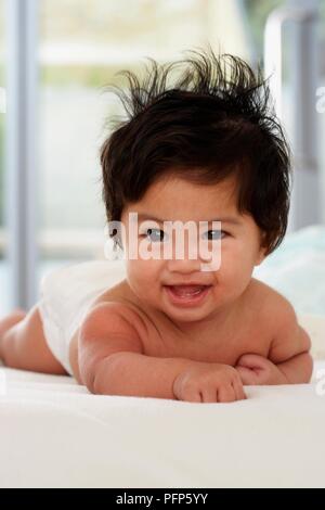 Bébé garçon avec les cheveux ébouriffés se trouvant sur l'avant Banque D'Images