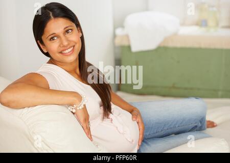 Sourire, femme enceinte, assise sur une chaise longue Banque D'Images