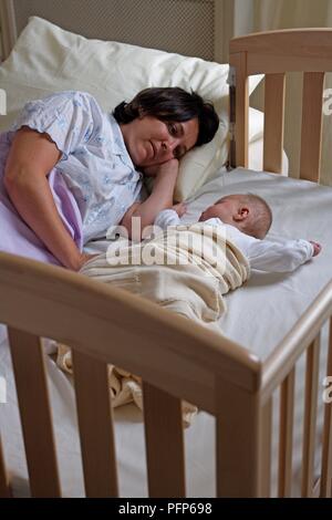 Femme couchée dans le lit à côté de fille de bébé lit chevet Banque D'Images