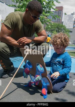 Le Cpl. Okoya Anderson, un commis d'entrepôt logistique de combat avec 23 Société à but spécial, Groupe de travail air-sol Marine Fleet Week de New York, passe de temps à interagir avec les enfants dans le cadre du projet Hope durant la Fleet Week New York, 26 mai 2018. Marines, marins, et gardes de la côte sont à New York pour interagir avec le public, faire preuve de capacités maritimes et enseigner les gens de New York de la mer. Banque D'Images