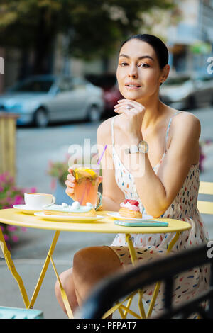 Femme paisible de toucher son menton tout en profitant de la limonade Banque D'Images