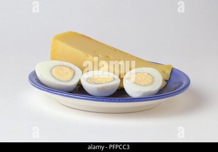 Tranche de fromage Edam et de trois moitiés d'oeufs durs sur plaque bleue Banque D'Images