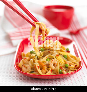 Ramasser des télévision de nouilles chinoises sautées avec le maïs, pois, Poulet et crevettes avec des baguettes Banque D'Images