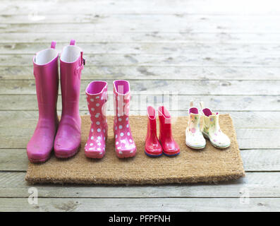 Sélection de bottes rose et blanc sur un tapis de porte Banque D'Images