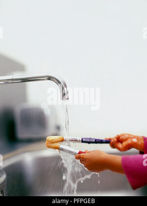 Girl Lave-pinceaux à l'eau courante au-dessus d'un évier Banque D'Images