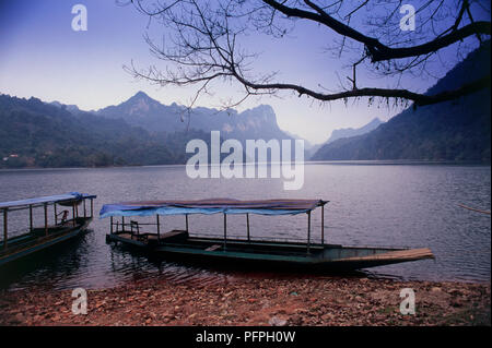 Vietnam, parc national de Ba Be, bateaux amarrés à bord du lac à l'aube avec décor de montagnes Banque D'Images