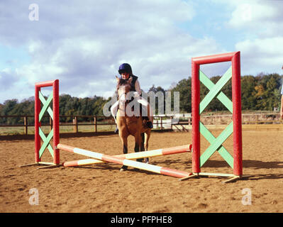 Young Girl riding pony sur franchi-rail dans l'enclos de saut Banque D'Images