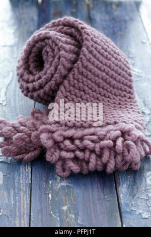 Écharpe en tricot rose boucle avec bordure sur fond de bois Banque D'Images