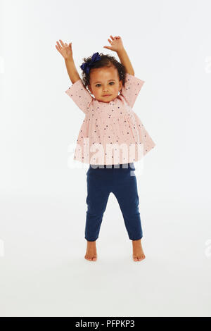 Petite fille en rose top jouant avec les bras en l'air (Modèle âge - 19 mois) Banque D'Images